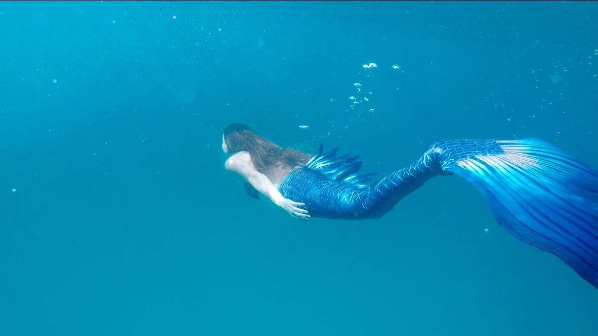 AquaMermaid mermaid freediving in open ocean with a blue silicone tail
